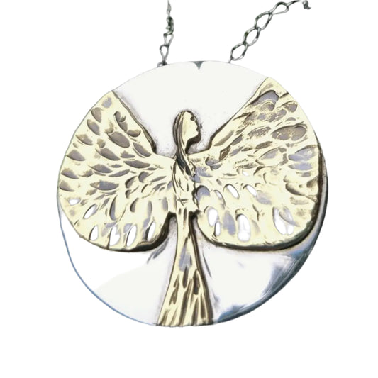 Close up of silver and gold angel necklace pendant on a white background.