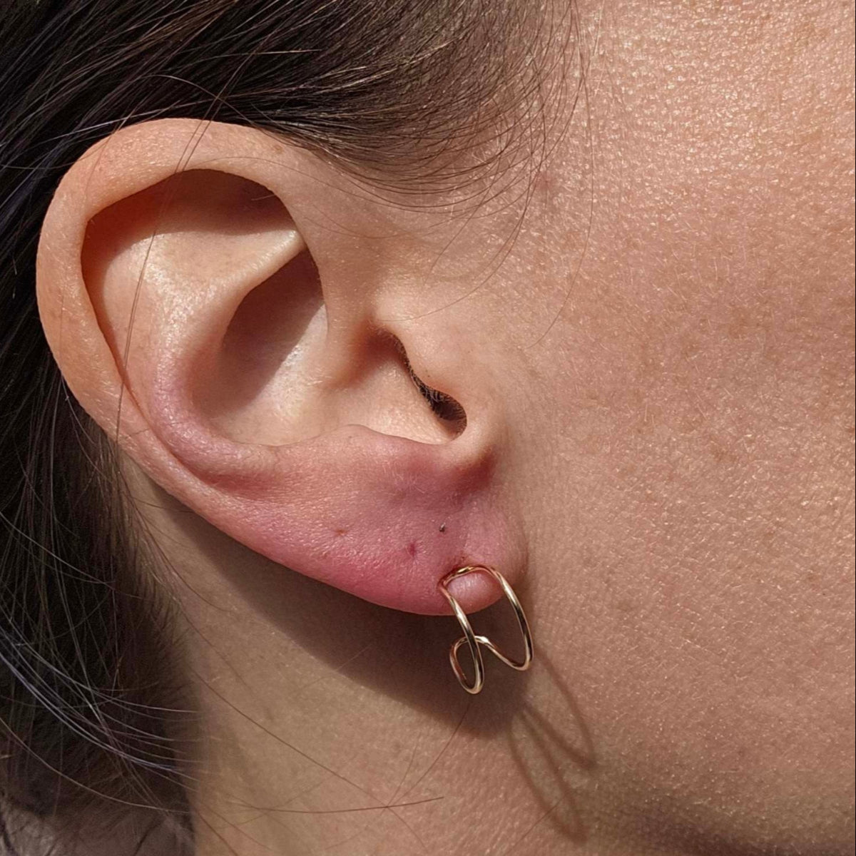 14K Gold lightweight earrings worn on a woman's earlobe