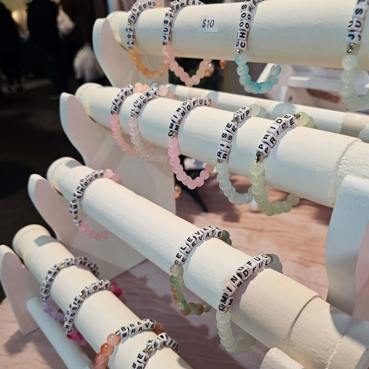 4 tier bracelet display unit with affirmation bracelets hung on each level.