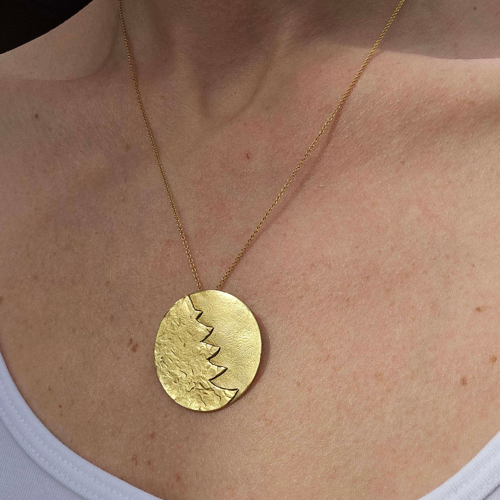 A gold Christmas necklace around a woman's neck.