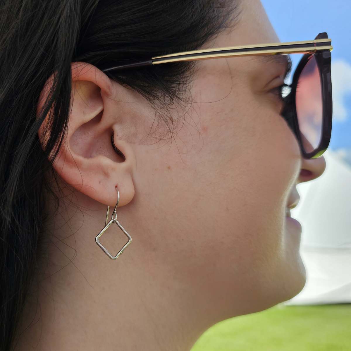 Woman with sunglasses and black hair wearing Silver square drop earrings.