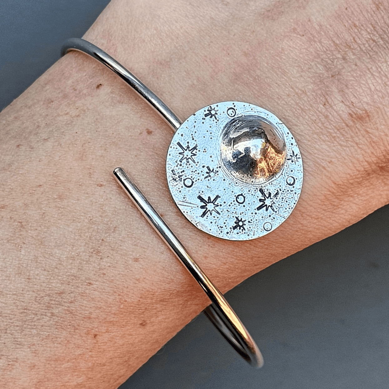 Reflections Moon bracelet in silver displayed on woman's wrist on grey background