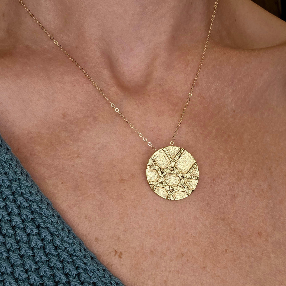 Close up of a gold Jewish star jewelry necklace hanging around woman's neck.