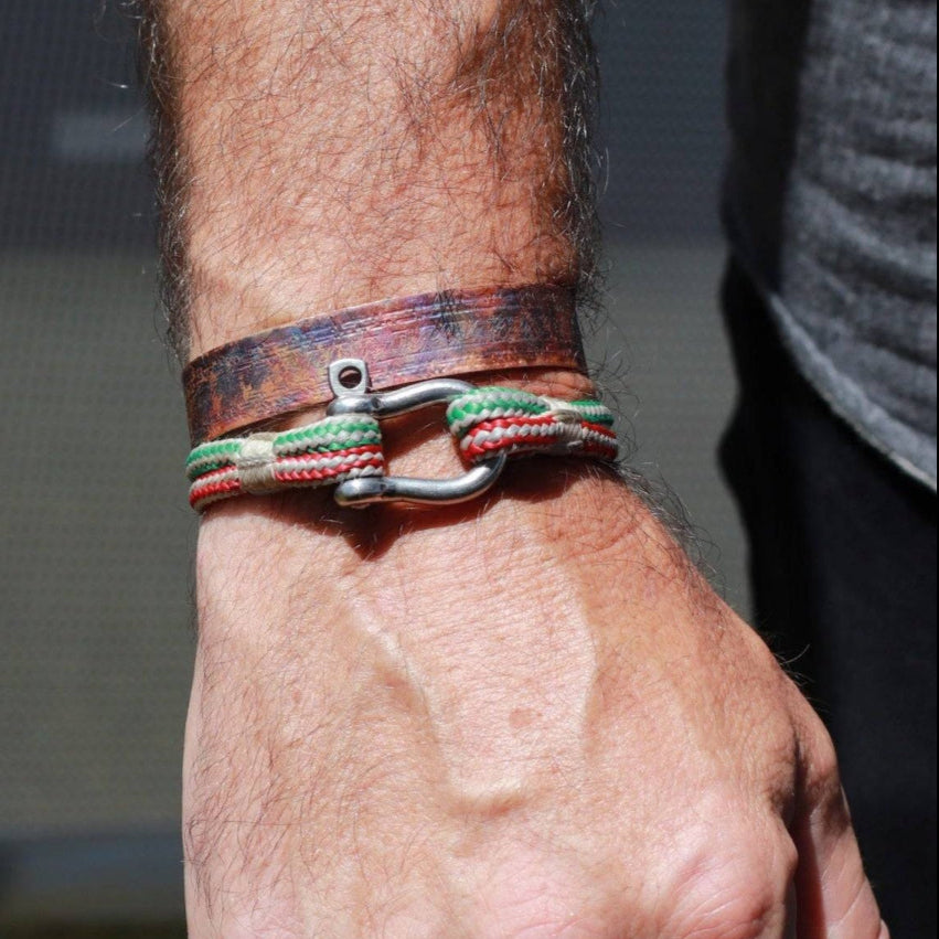 flame painted copper cuff bracelets modeled on man's wrist with anothe string bracelet below it.