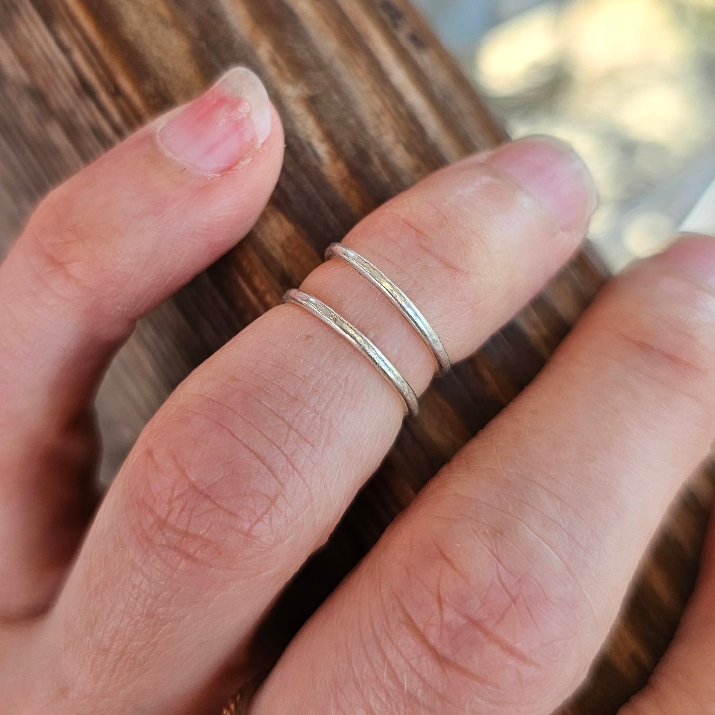 Inspirational above the knuckle Silver Midi Ring on woman's finger atop wooden rail.