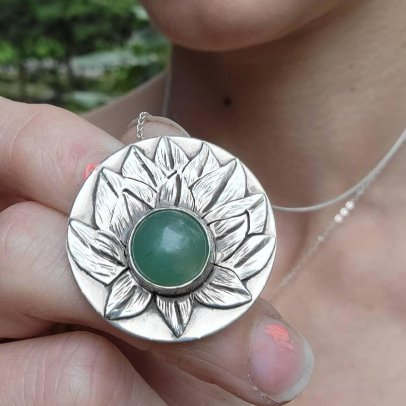 Woman holding a lotus flower pendant necklace in her fingers to show it up close.
