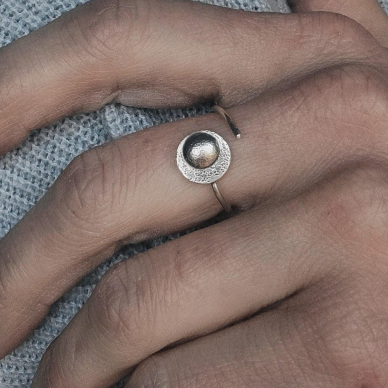 Silver adjustable moon ring worn on a woman's hand.