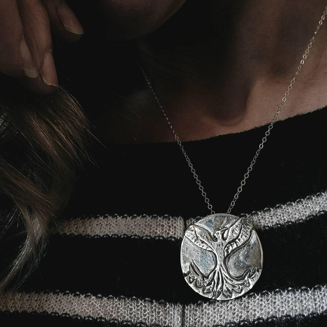 Woman with black and white striped sweater wearing silver Phoenix necklace.