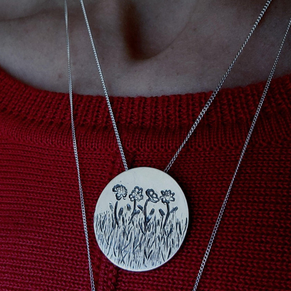 Birth Flower Necklace on elegant chain worn around a woman's neck with another necklace chain framing it.