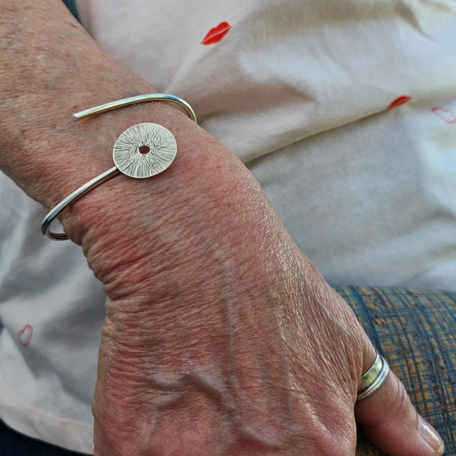 Silver bracelet on woman's wrist and silver spinner ring on thumb