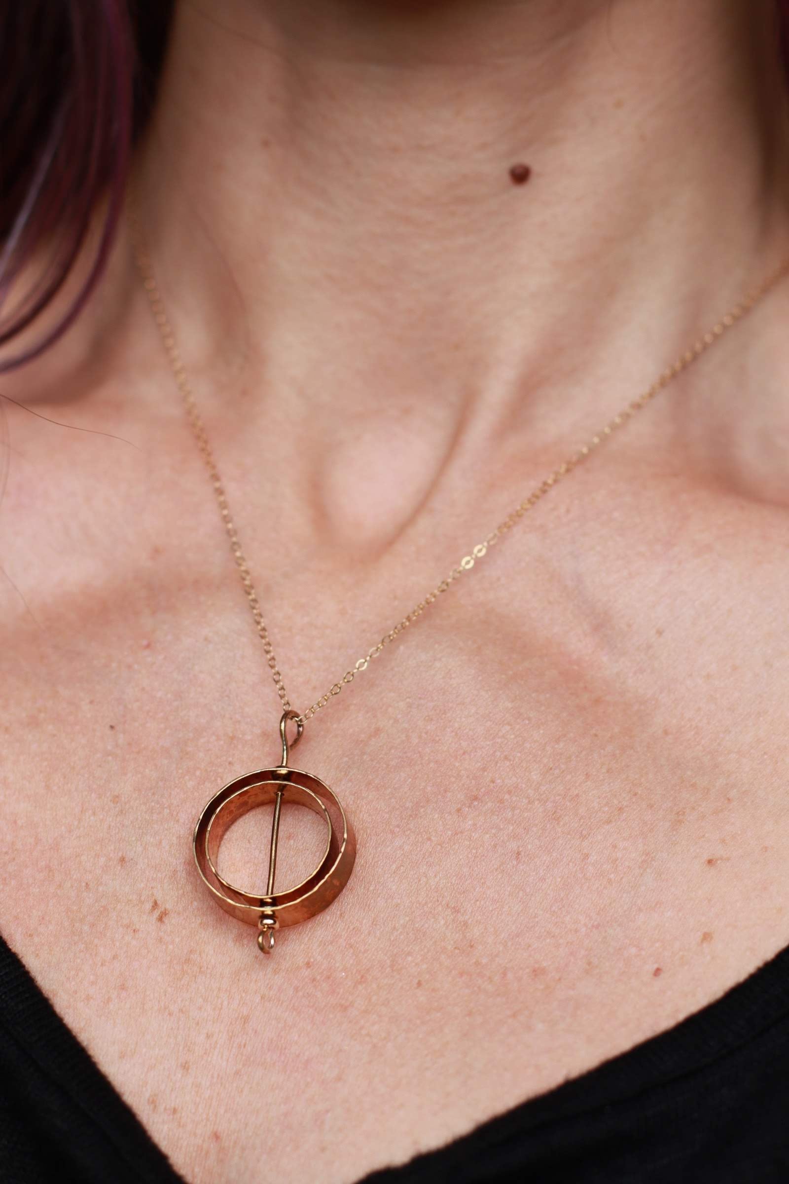 Gold Karma necklace modeled on a woman in a black t-shirt.