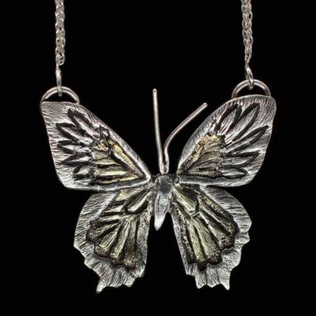 Close up of Jaclyn Nicole's one of a kind butterfly necklace hand fabricated in sterling silver and brass