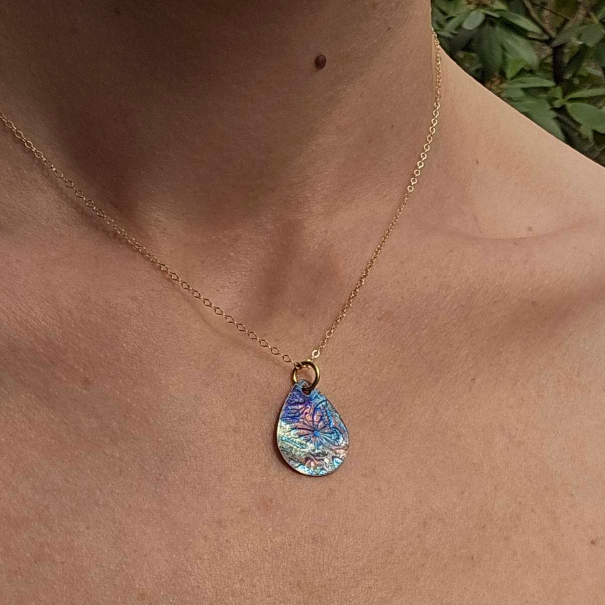 Flame painted copper pendant necklace  worn on woman's neck.