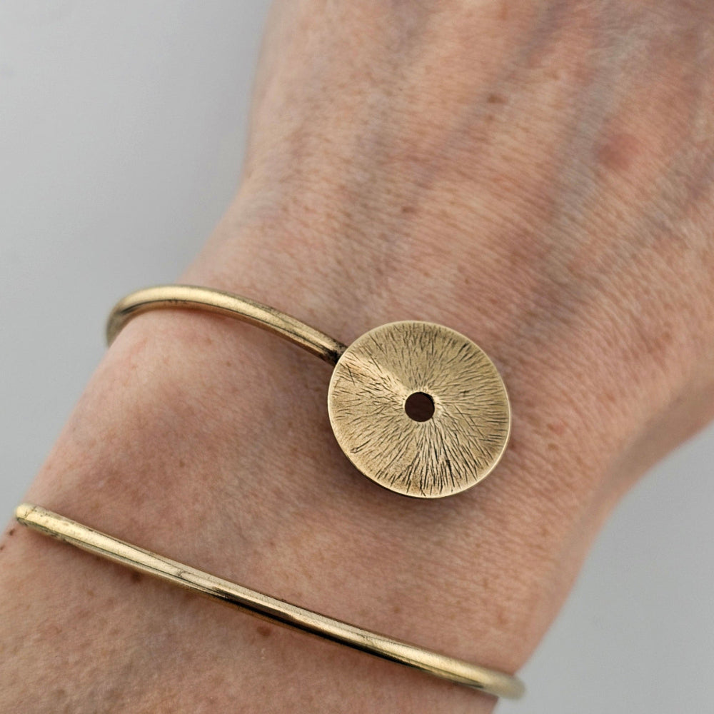 Gold Manifestation bracelet cuff on a woman's wrist.