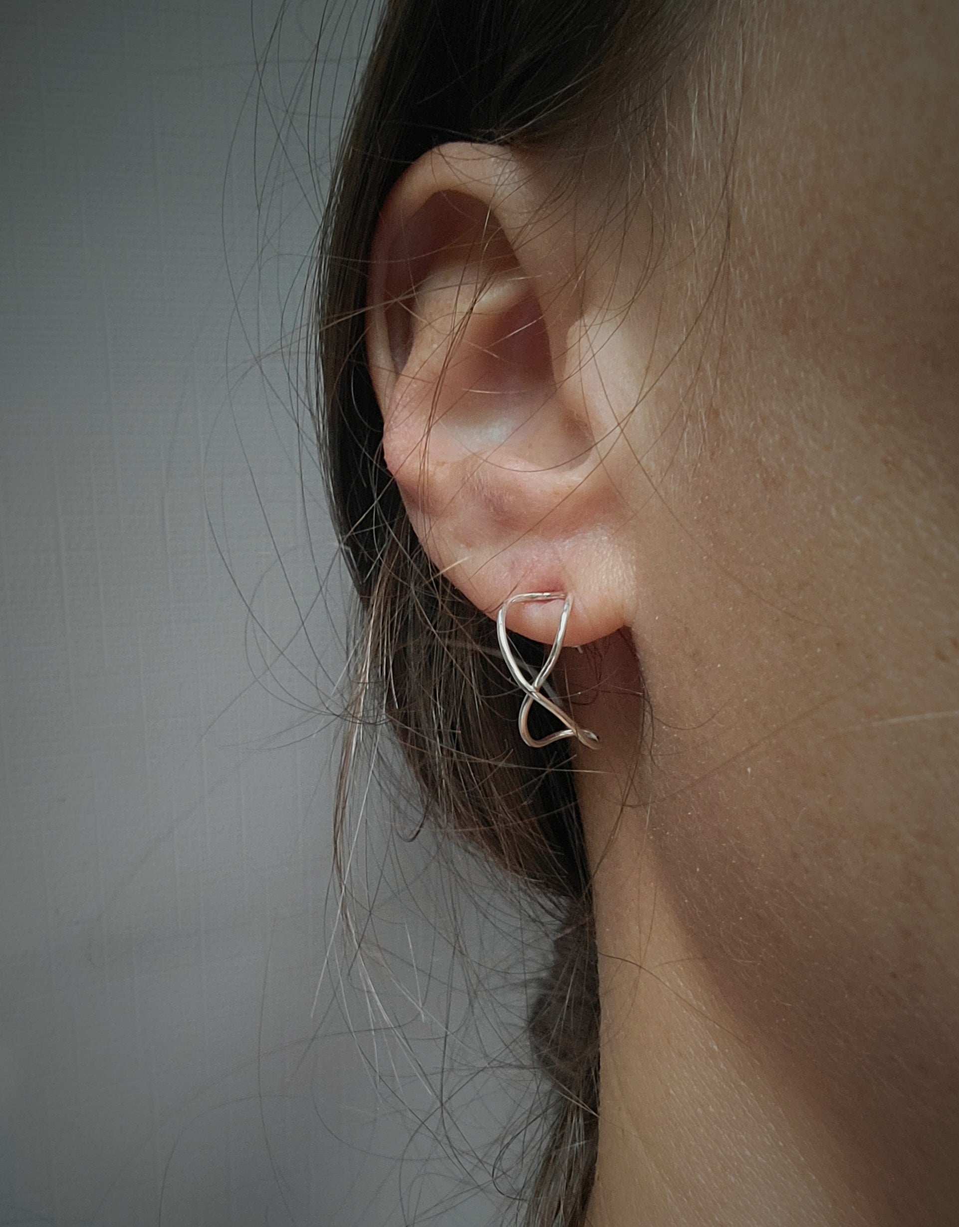 Meaningful jewelry infinity earrings in sterling silver worn on a woman's ear.