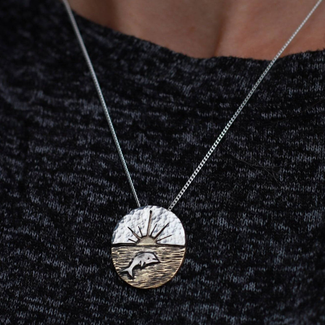 Handcrafted- Dolphin Sunset Necklace worn on woman's neck.