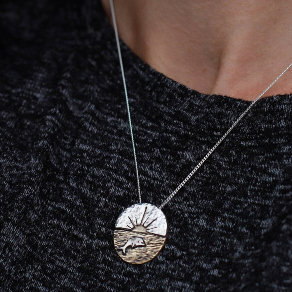 Artisan-Crafted-Dolphin-Necklace-With-Sunset-Backdrop worn around woman's neck