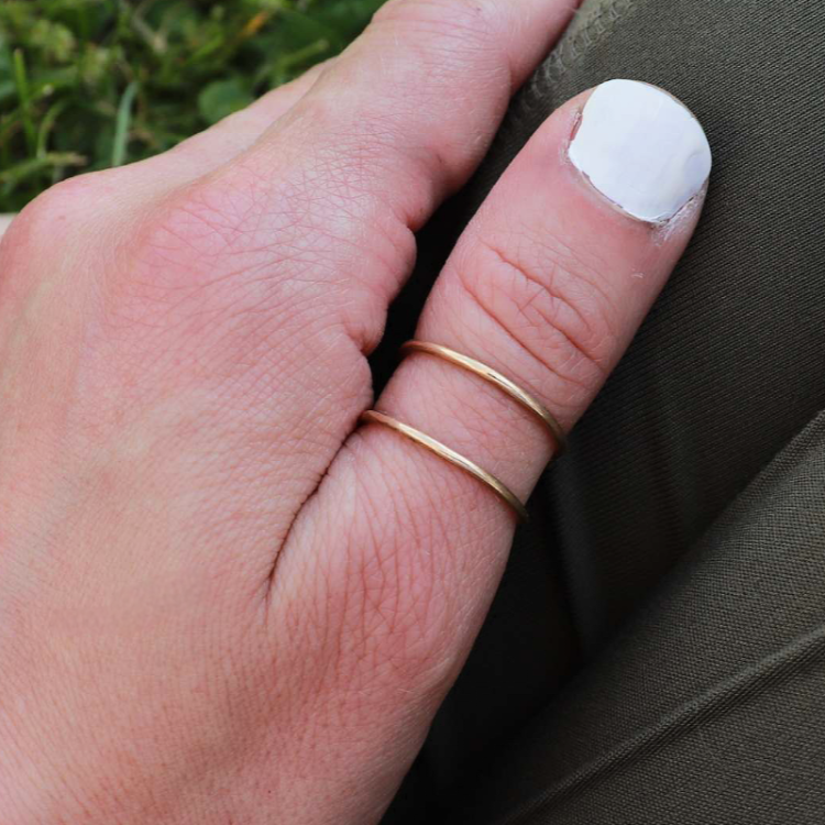 Woman wearing gold space between ring on her thumb.
