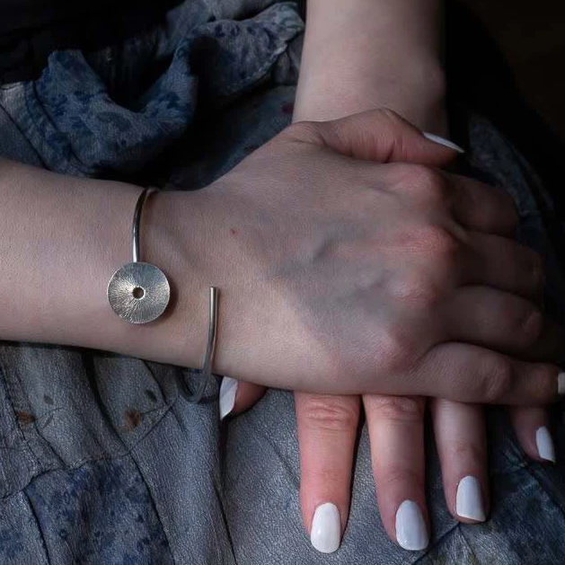 hands folded wearing a sterling silver bracelet