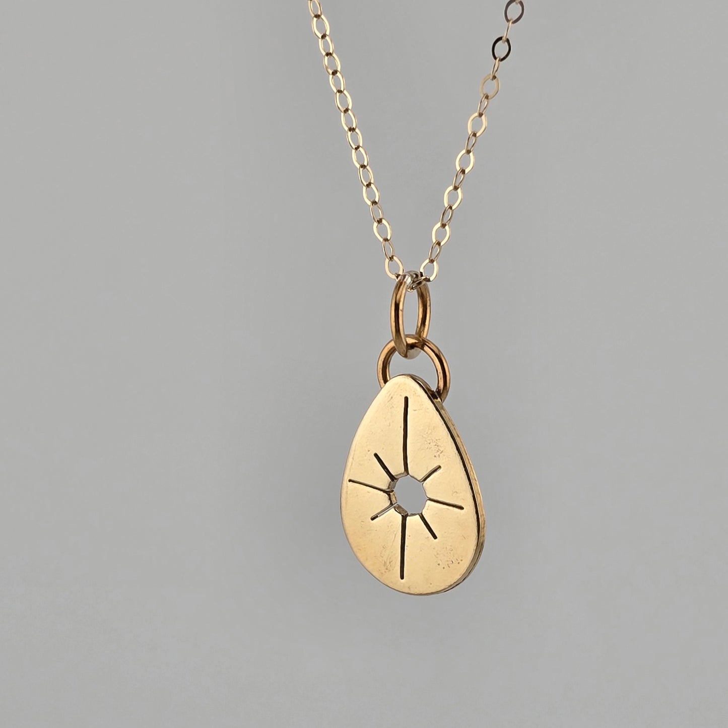 Gold pendant necklace on a gray background