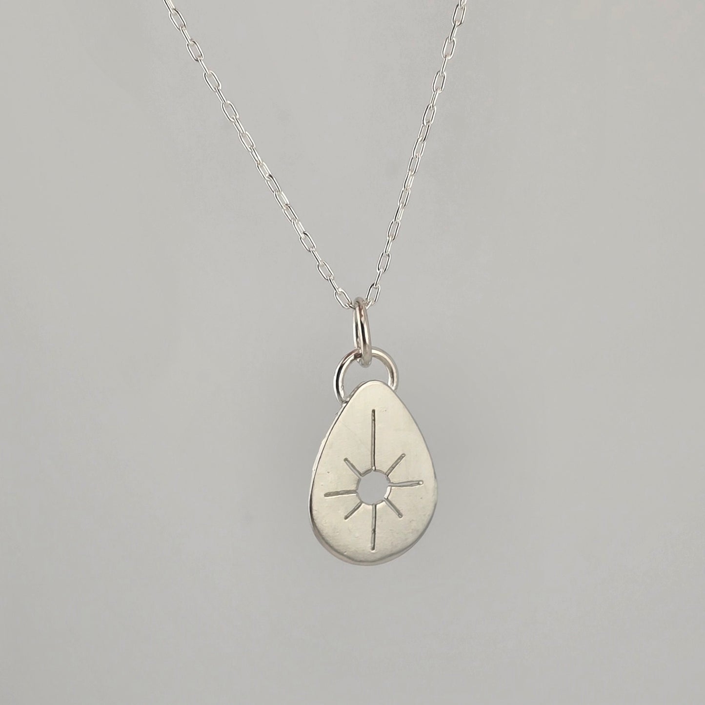 Silver teardrop pendant necklace on a gray background