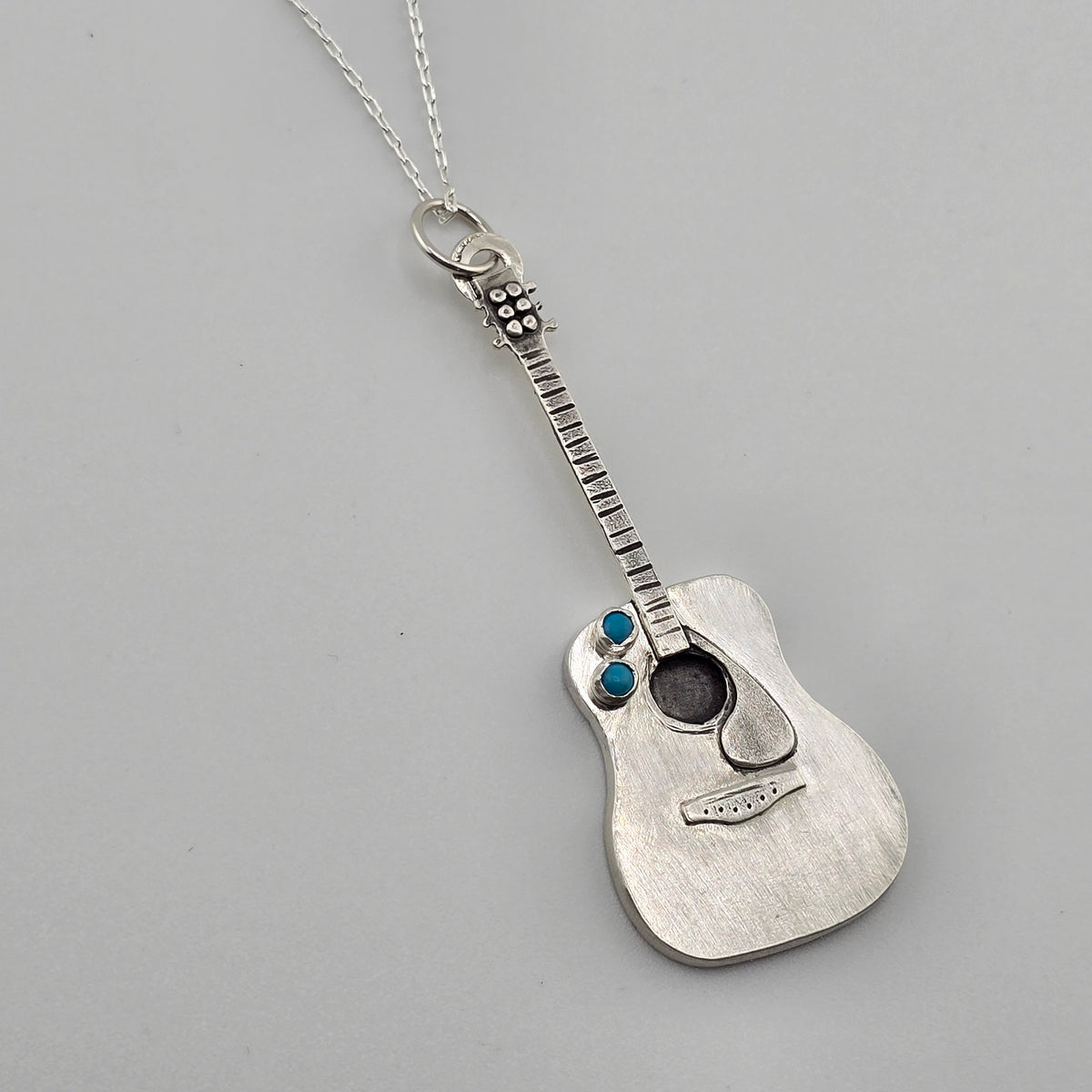 Full pendant shot of a fully handmade silver guitar necklace made by Jaclyn Nicole. 