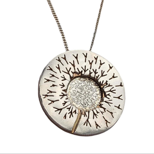 One of a kind handcrafted dandelion necklace worn on woman's neck over a white shirt.