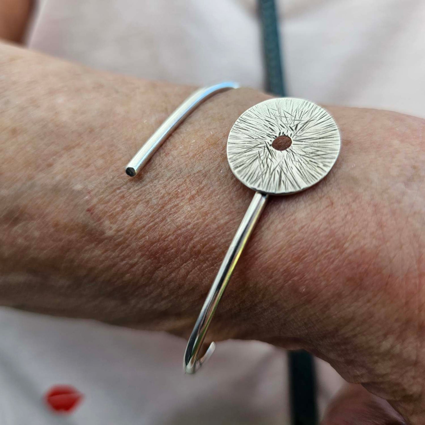 a sterling silver wrap-around manifestation bracelet on a  wrist