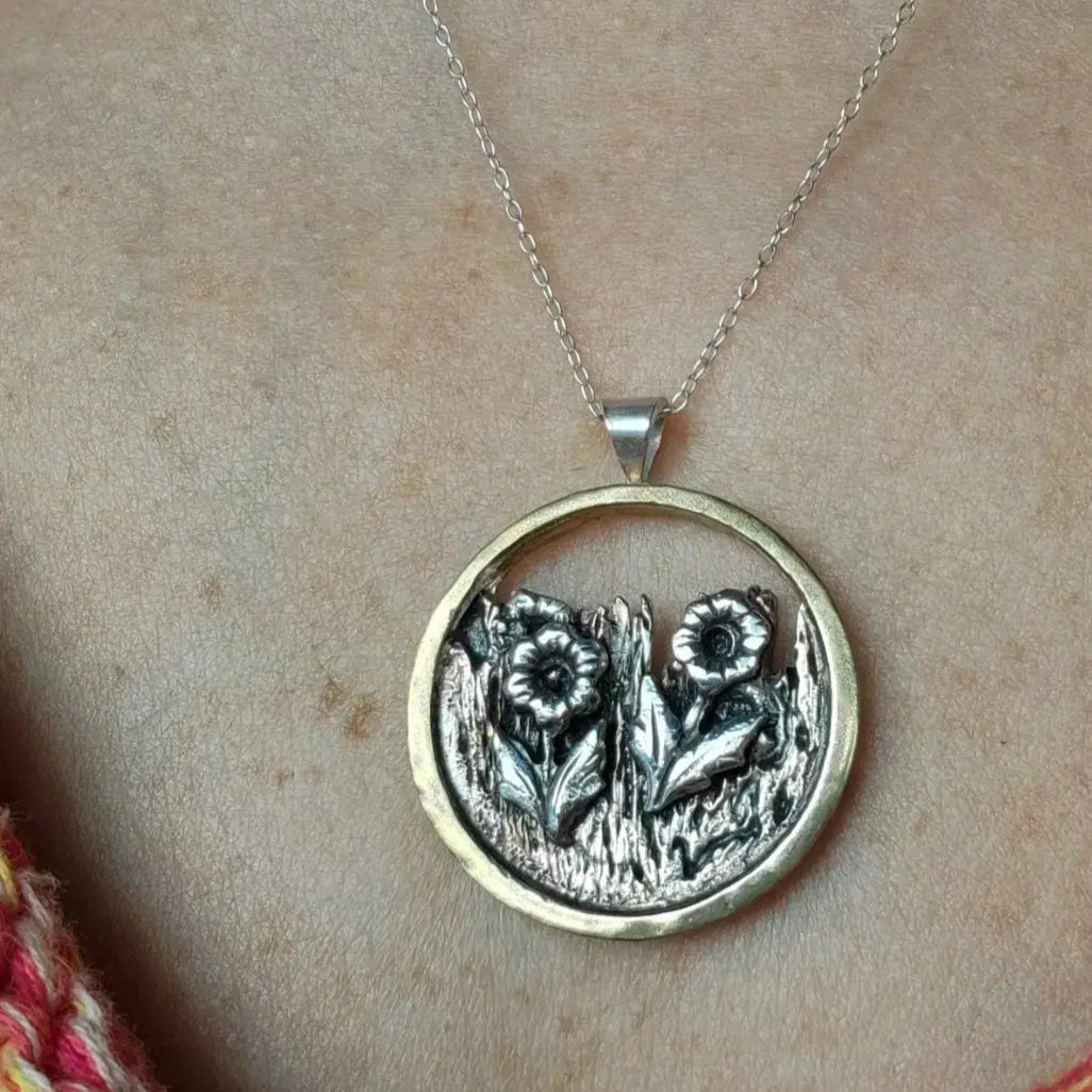 Brass, Copper and Silver flower garden necklace worn around woman's neck with an orange sweater peeking out at the bottom