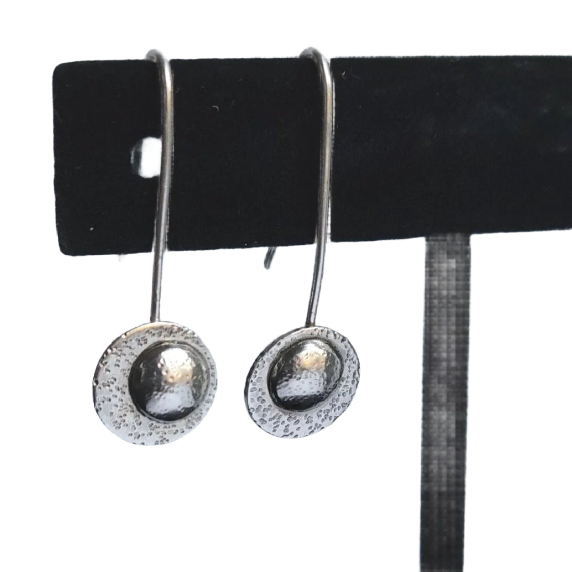 Sterling silver drop moon earrings hanging on a black velvet earring display.